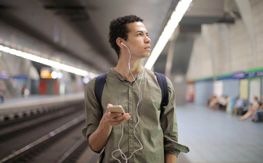 How to Upload Your Podcast to Multiple Platforms (2023) 1 man listening to podcasts on train underground platform