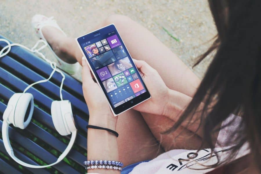 Why Does My Podcast Stop Playing When My Phone Locks? 1 white woman checks windows phone with headphones nearby