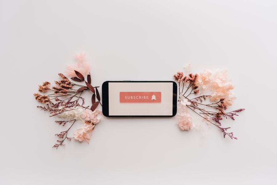 How Many Podcast Episodes Should You Launch With? 24 Flat Lay of Dried Flowers and Mobile Phone with Subscribe