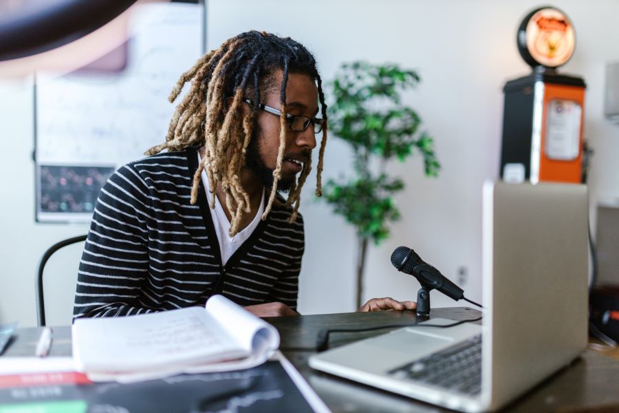 SoundCloud vs Spotify: Podcast Hosting Platforms Compared 1 Man Sitting In Front of a Laptop and Microphone
